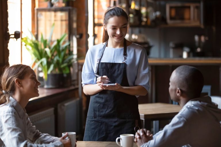 Smiling waitress takes the order of a happy couple in a restaurant.