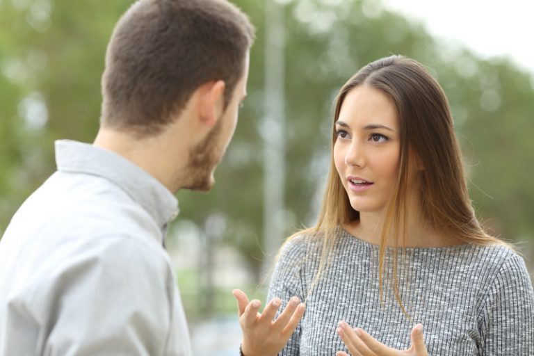 Couple having a conversation while standing outside.