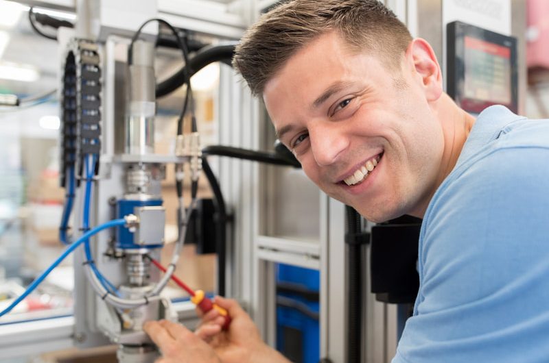 Male engineer working on a machine in a factory.