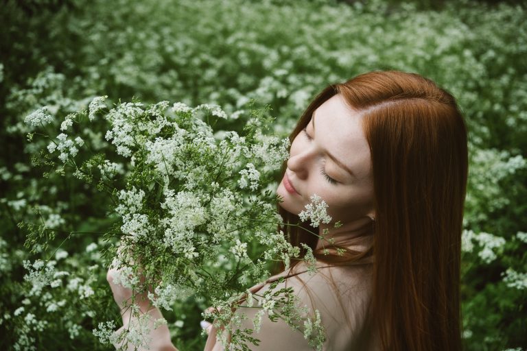 A woman smelling a handful of flowers.
