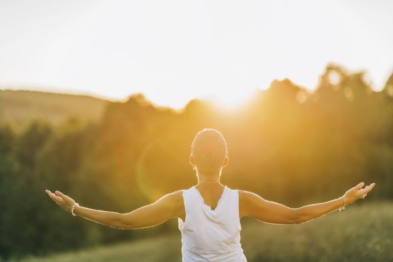 A woman embracing the sun, with her arms wide open. 