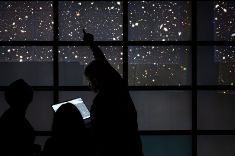 People looking through a window up at the stars.