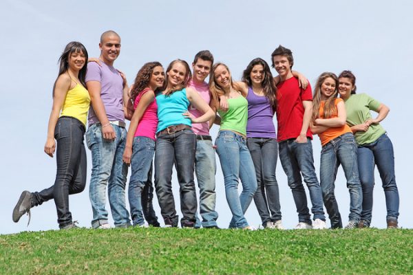 A smiling group of teens outside posing for a group photo.
