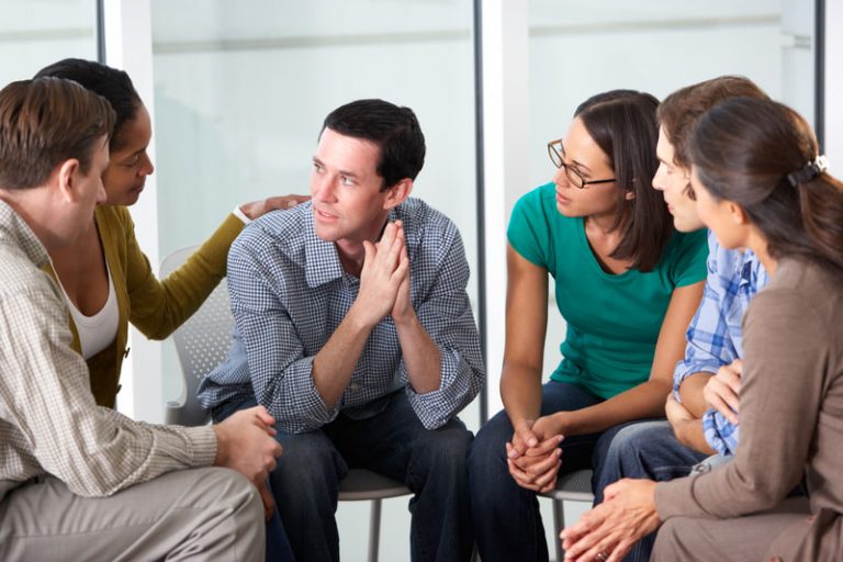 Support group meeting where people are sitting in chairs arranged in a circle.