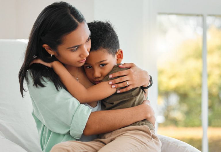 Young mother holds her son in her lap, comforting him.