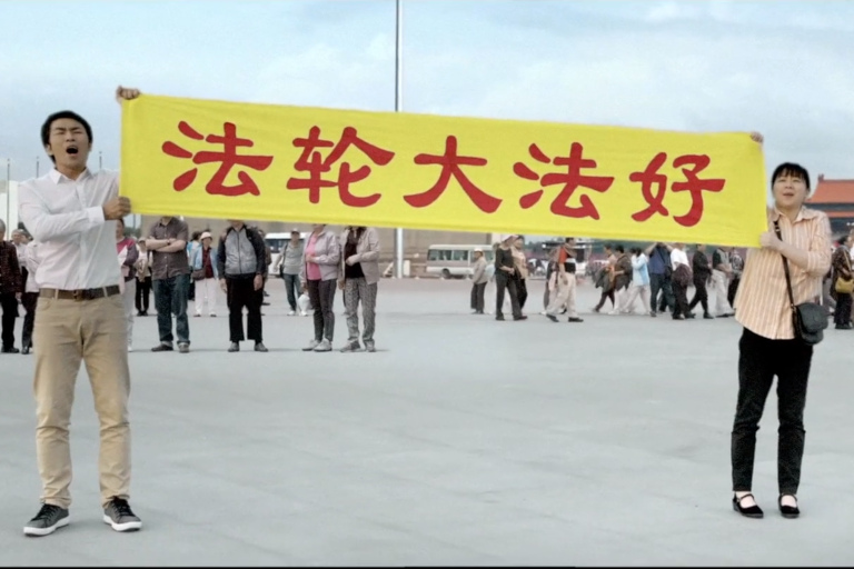 From the film 'Coming For You,' Dawei Liu and his wife hold up a banner on Tiananmen Square that says 'Falun Dafa is Good' in Chinese characters.