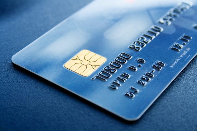 Glossy closeup of a blue credit card sitting on a dark blue background.