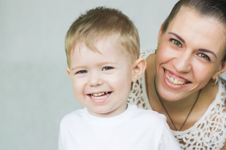 Mother and her young son give big smiles to the camera.