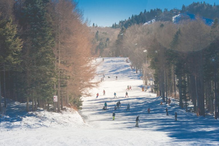 Beautiful landscape view of a mountain covered with white snow and people skiing at a ski resort in Japan.