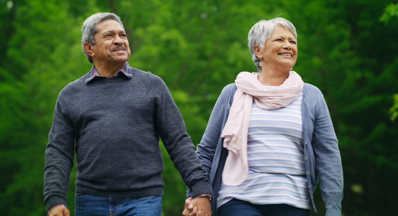 Mature couple holding hands and walking together outside.