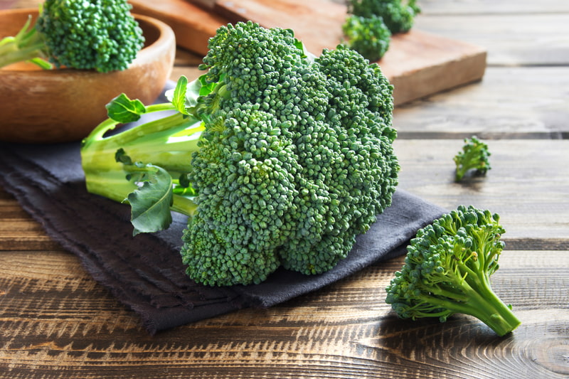 Fresh broccoli sitting on a wooden table.
