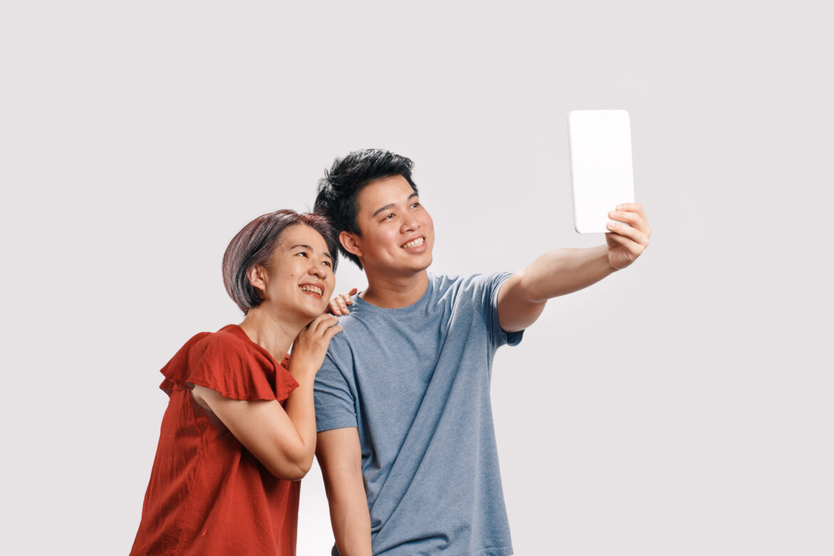 A smiling mother and son taking a selfie together, highlighting their close bond.