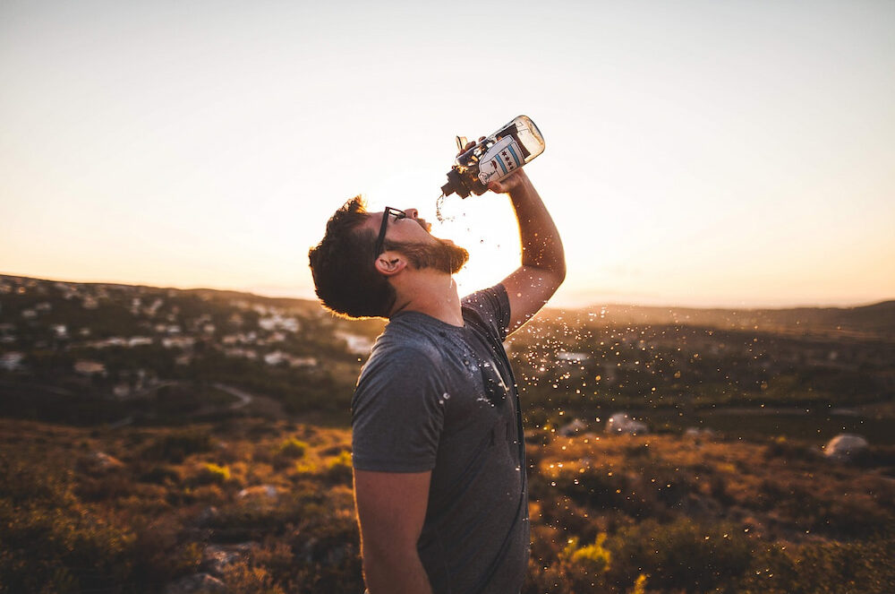 A man drinking water while on a hike.