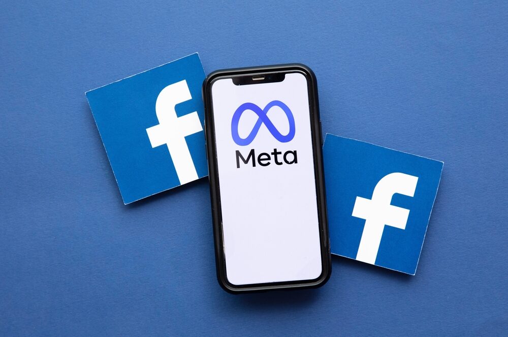 Facebook logo on a blue background next to a smartphone with the Meta company logo on the screen.