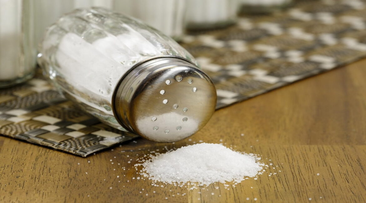 A salt shaker with spilled salt.