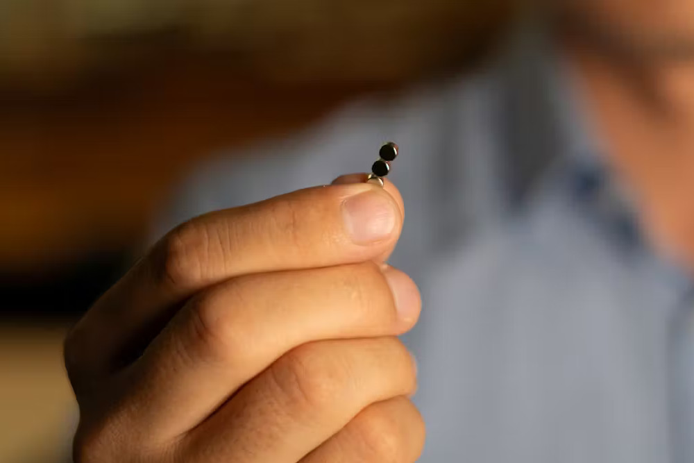 Man holding tiny magnets used to power new microsurgery tools.