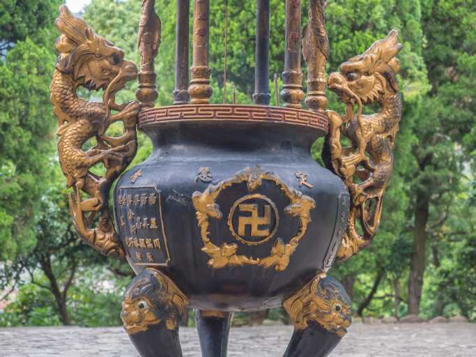 A black censer with two golden handles in the shape of dragons and the wan sign (or swastika) on the front.
