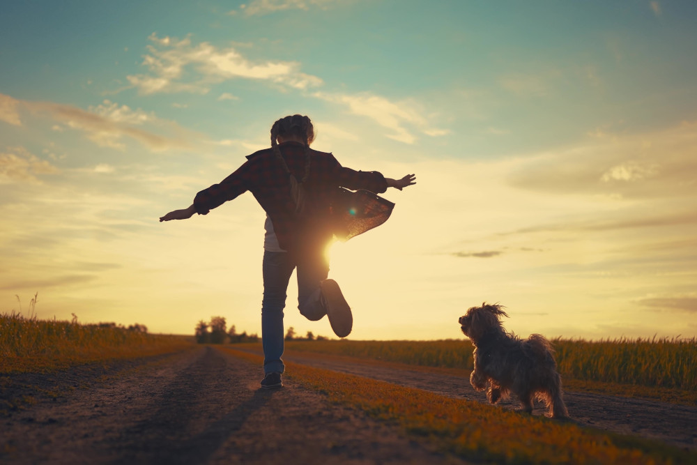 A young girl running with her little dog.
