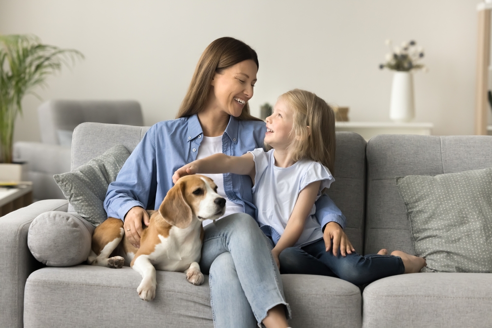 A mother daughter, and dog cuddling on the sofa.