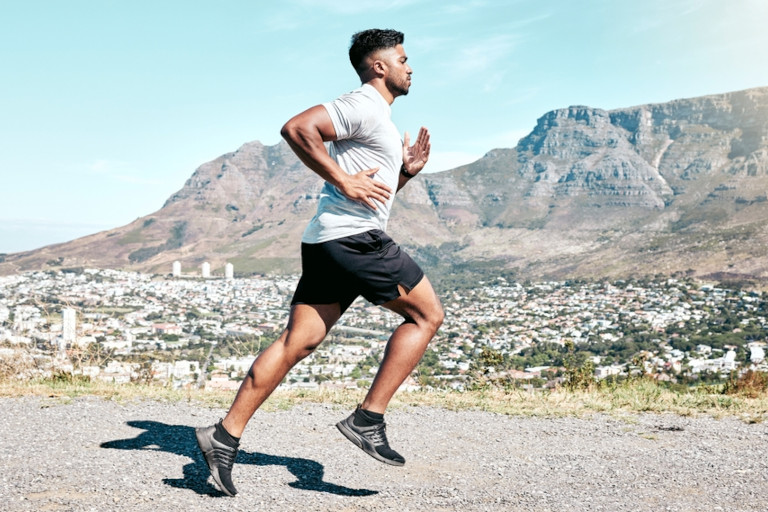 Man running outside with mountains in the background.