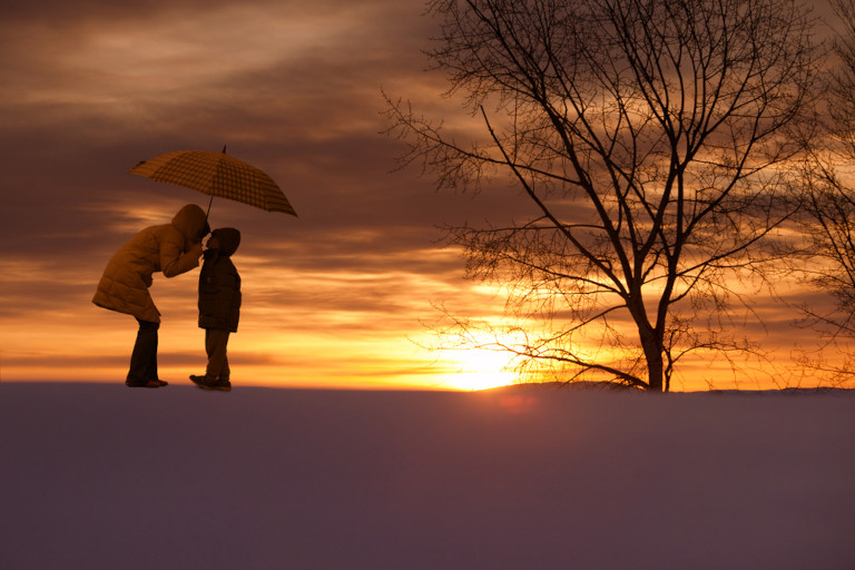 Asian mother and son under an umbrella at sunset