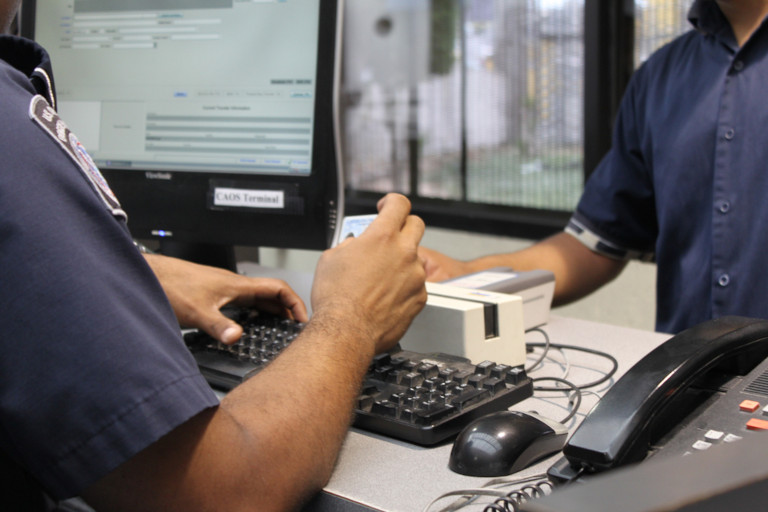An official checks a man's ID before letting him enter a secure area.