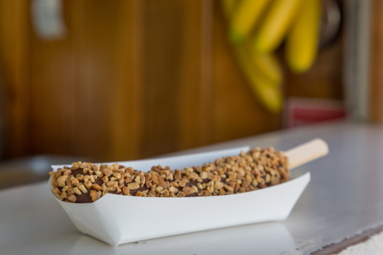Banana dipped in chocolate and rolled in peanuts ready to be served to a customer.