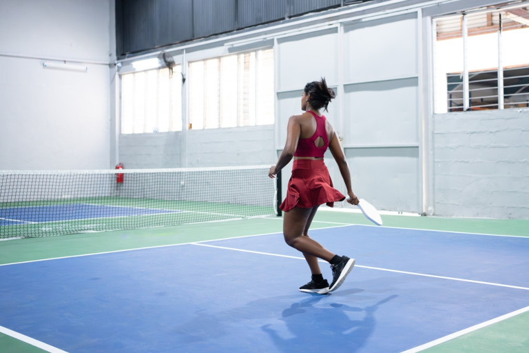 Young athletic woman playing pickleball at in indoor court.