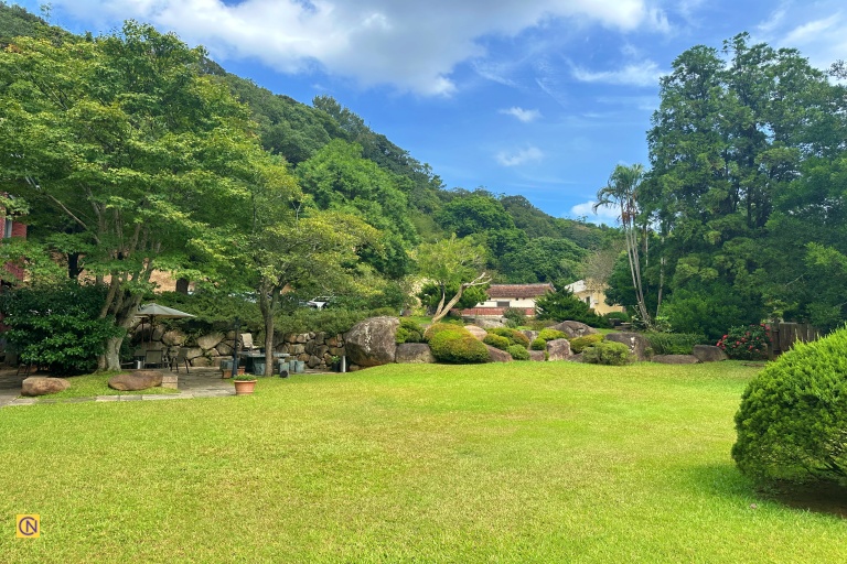 The restaurant’s spacious lawn is bordered by tall trees and vibrant greenery.