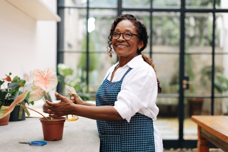 Happy African American lady re-potting a plant.