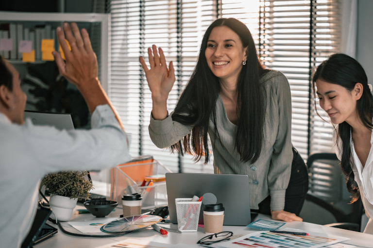 Young woman giving a 'high-five' to a co-worker in the office.