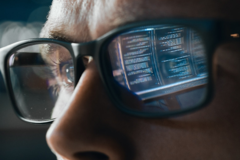 Software engineer with lines of code reflected in the lens of their glasses.