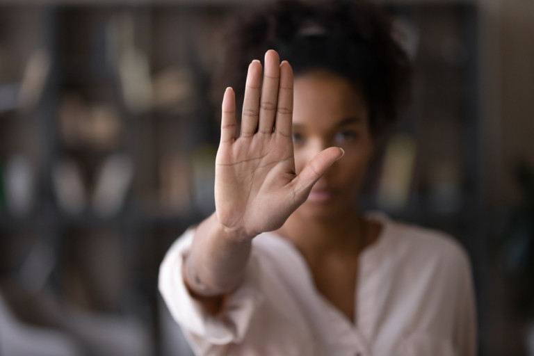 Woman with a serious expression on her face holding her hand up telling someone to stop.