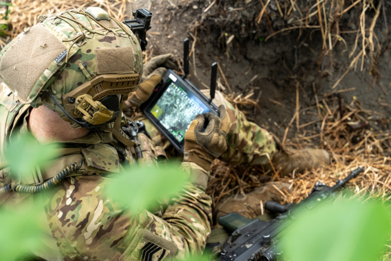 A soldier in the field with a control tablet to operate a UAV.