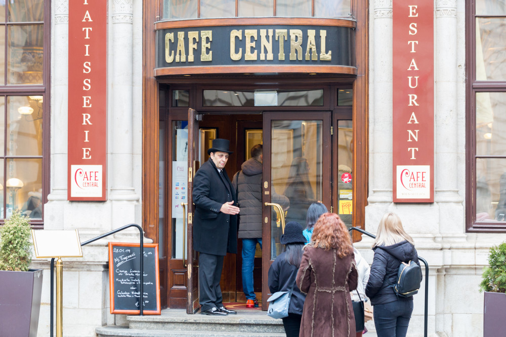 A doorman greeting guests as they approach a famous coffee house in Vienna.