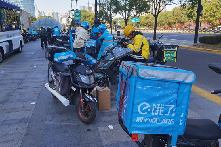 A group of food delivery drivers with their scooters in China.