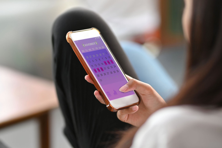 Woman looking at an app on her smartphone that tracks her menstrual cycle.