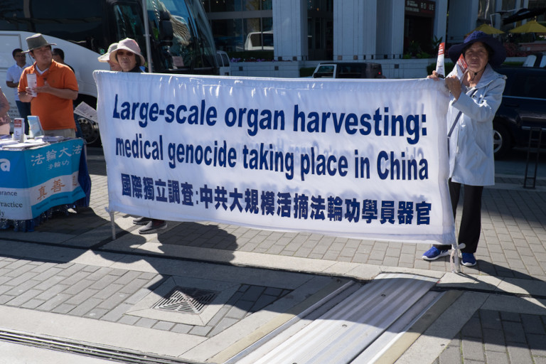 Chinese women holding a banner asking for an end to China's large-scale organ harvesting of prisoners of conscience, largely taken from Falun Gong practitioners who refuse to give up their faith.