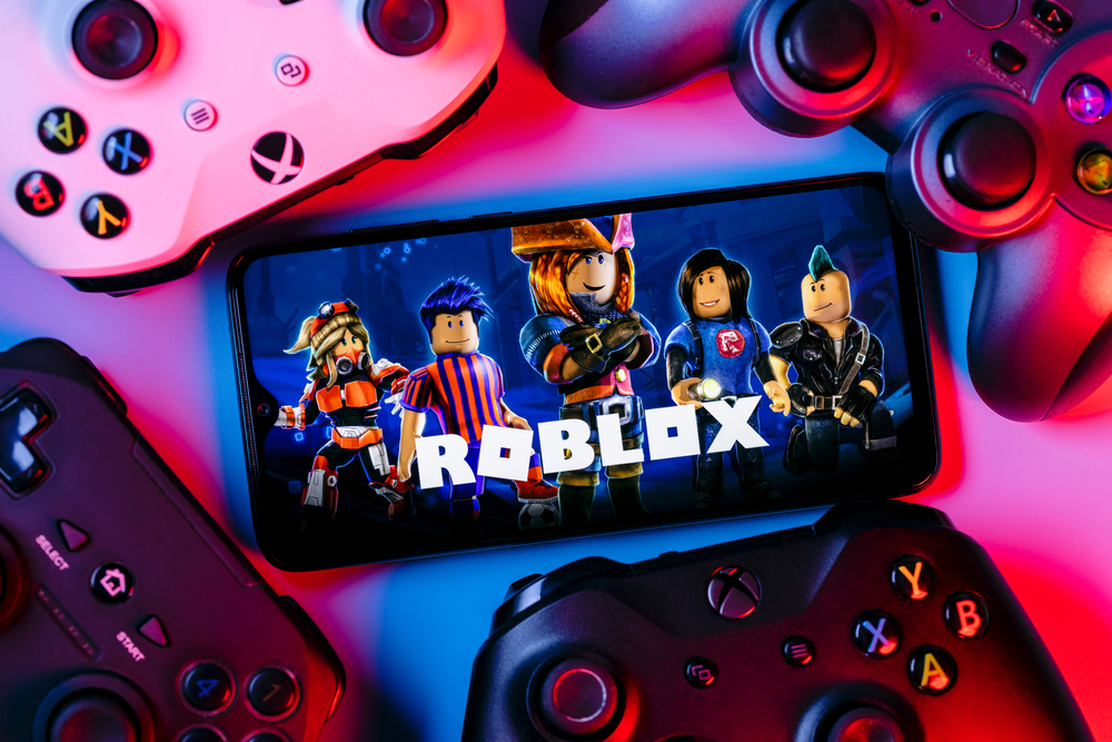Roblox video game on a smartphone screen surrounded by game controllers.