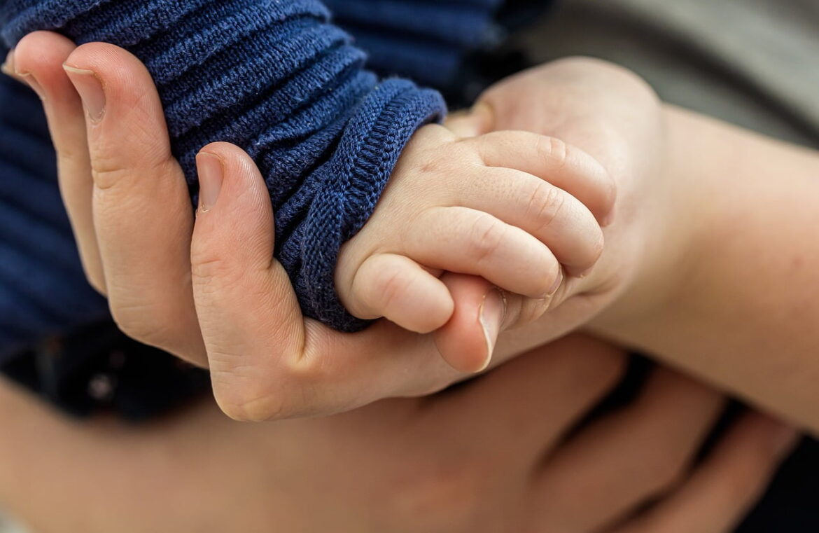 A child's hand touching an adult's hand.