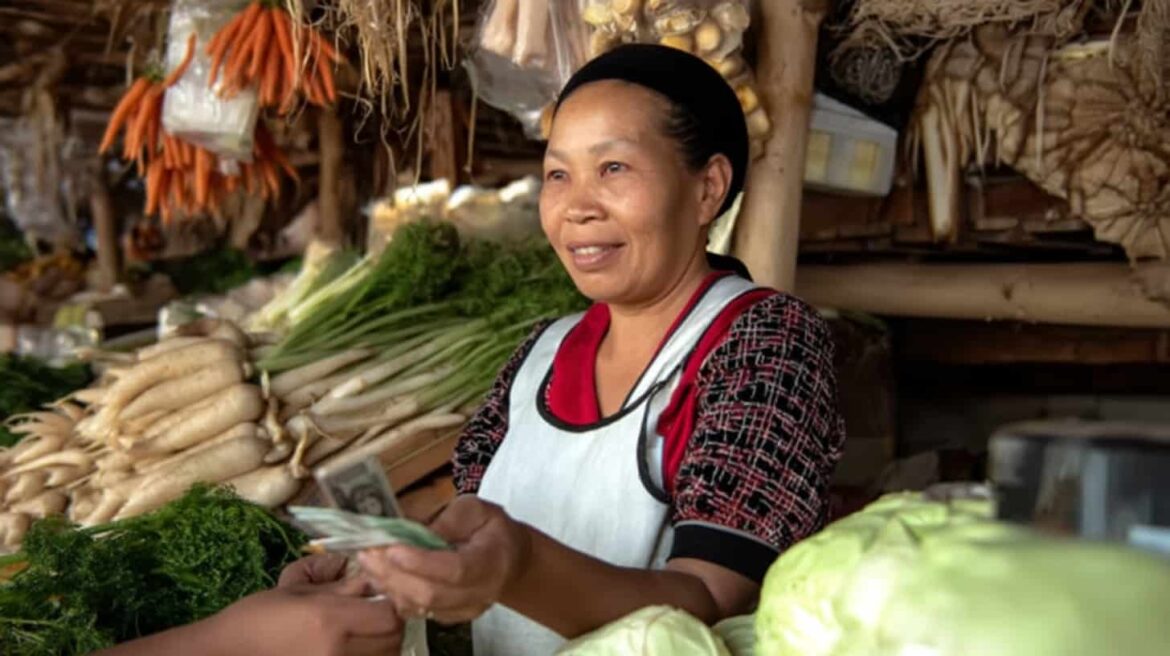 Asian woman selling vegetables, symbolizing a day in the life of one of the most unlikely philanthropists.