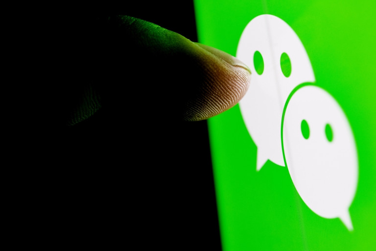 Finger pointing to the WeChat logo on a screen.