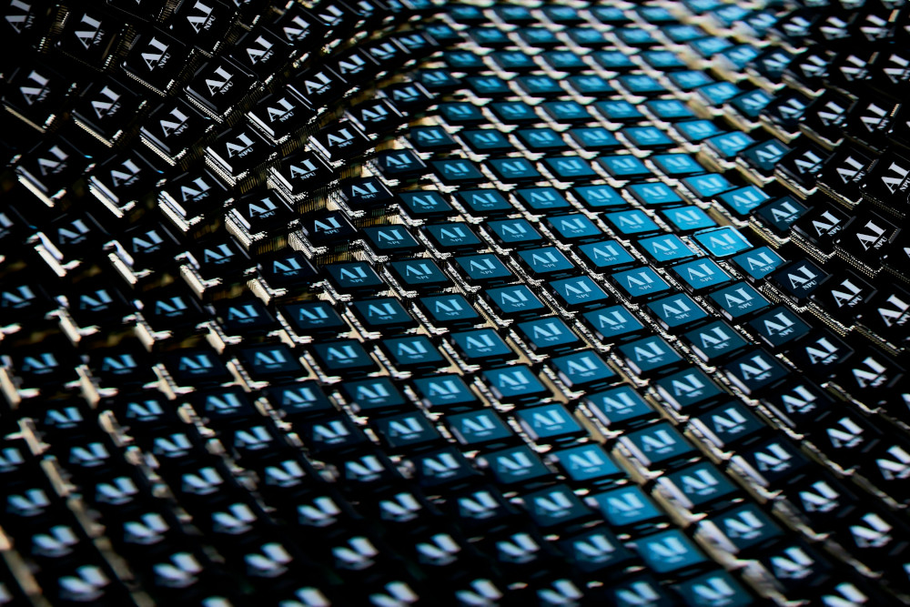 Image of numerous AI-branded microchips arranged in curved, repeating rows, creating a futuristic, patterned visual effect.