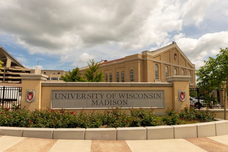 Closeup of the University of Wisconsin - Madison welcome sign with Badger fieldhouse in the background.