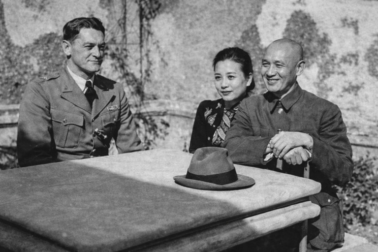 Image of Claire Lee Chennault seated outdoors with Soong Mei-ling and Chiang Kai-shek during a wartime meeting, captured in a sunlit garden.