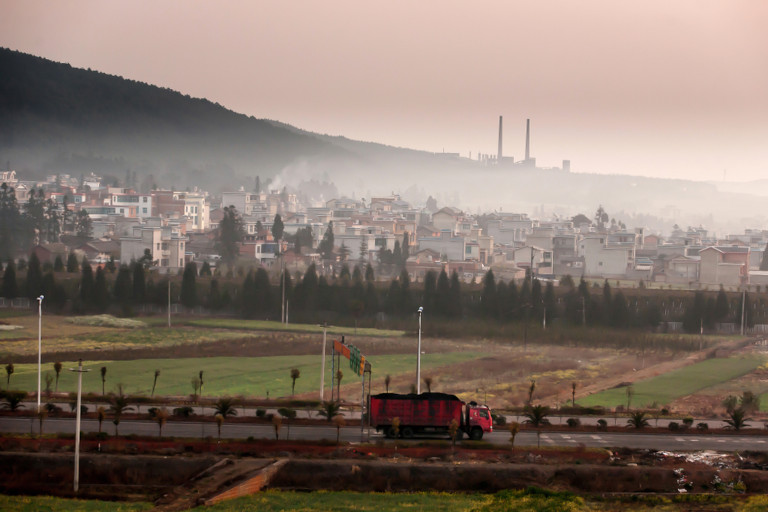 A coal town in South China, with a coal power plant on the mountain and a truck loaded with coal on the road.