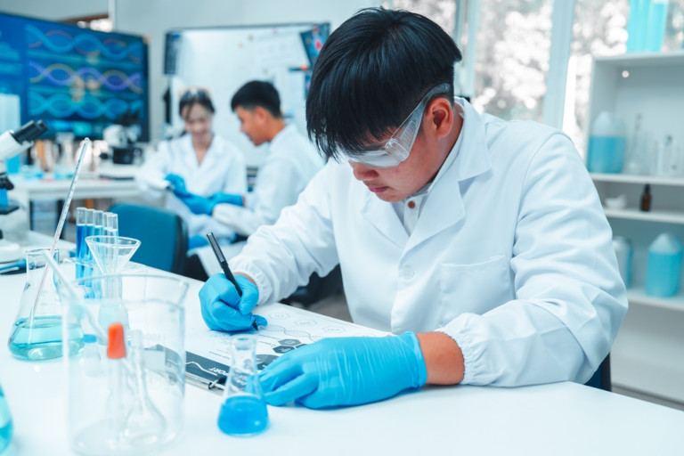 Students working in a laboratory writing results of an experiment.