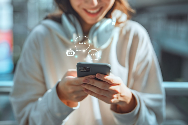 Images of a chatbot superimposed on a photo of a smiling young woman using her smartphone.