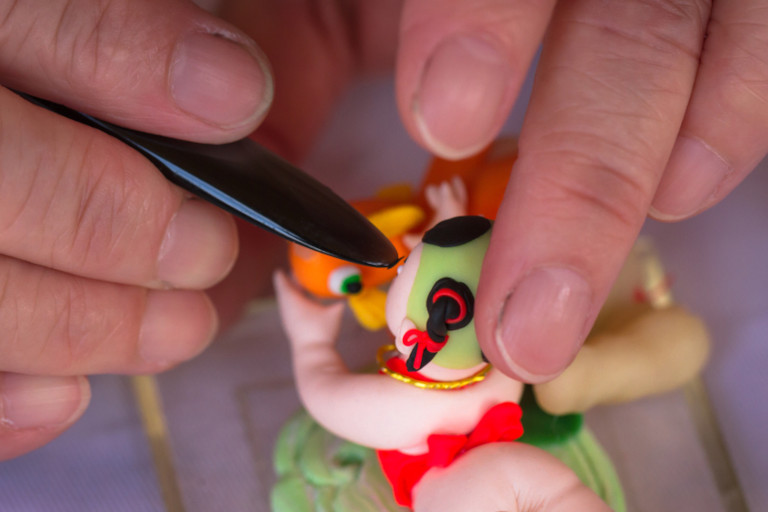 Closeup of an artist's hands as he crafts a dough figurine.