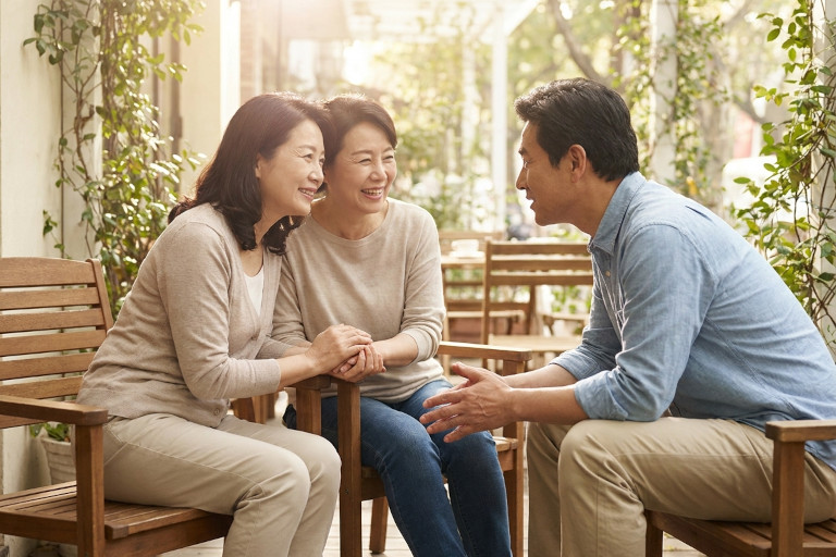 Image of three friends sitting outside in a courtyard, smiling and talking.